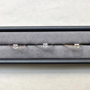 Three Asscher cut Moissanite rings in rose gold, silver, and gold finishes on velvet