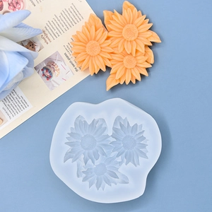 Macro view of sunflower silicone mold with orange resin flower crafts on blue background
