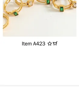 Detail of gold-plated twisted rings featuring green and clear baguette-cut cubic zirconia