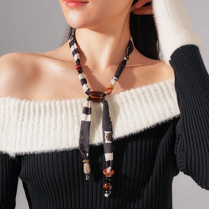 Close-up of black and white plaid fabric ribbon with decorative wooden beads necklace