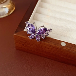Détail d'une bague papillon avec cristaux de zircon violets sur écrin en bois