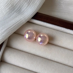 Close-up of pink mermaid pearl stud earrings with iridescent luster in a white velvet box