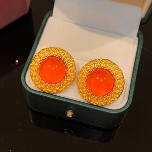 Detailed view of vintage round gold earrings with orange gemstones in a green jewelry box