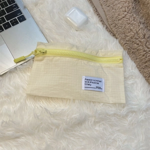 Detailed view of yellow plaid luggage organizer with zipper and woven label on plush surface