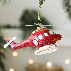 Sparkly red helicopter Christmas tree ornament hanging on green branches with festive lights