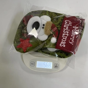 Detail view of a green Christmas stocking with snowman on a scale weighing 56.8g