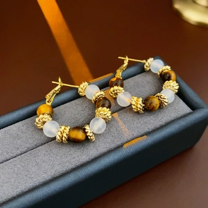 Detail of gold-plated hoop earrings with tiger eye beads in a velvet jewelry box
