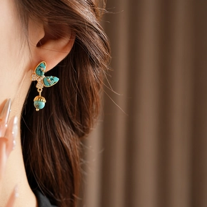 Gros plan de boucles d'oreilles papillon plaquées or avec pierres turquoises sur modèle