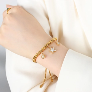Adjustable gold beaded bracelet with crystal starfish and round pendants on wrist