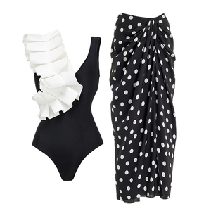 Detail of black swimsuit with 3D white ruffle shoulder and polka dot wrap skirt