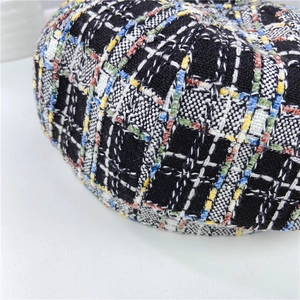 Close-up of multicolor plaid tweed fabric texture on a retro autumn beret hat