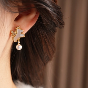 Détail de boucle d'oreille papillon en or 18k avec nacre et perle blanche pendante