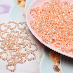 Detailed view of heart-shaped peach faux pearl beads in a ceramic bowl for DIY crafts