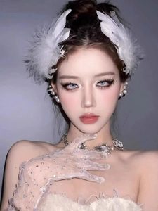 Close-up of white feather hair clip with pearl earrings and lace gloves on model