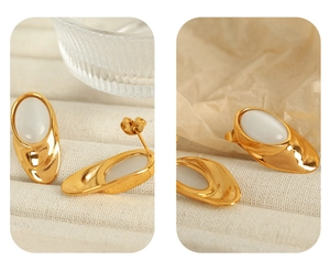 Macro shot of gold-plated oval stud earrings featuring translucent white opal stones