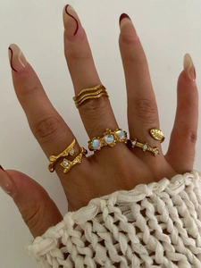 Set of five gold boho rings with moonstone and wave patterns worn on a model's hand