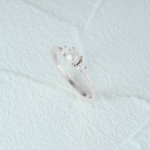 Macro shot of silver S925 ring featuring a lustrous round pearl and side gemstones
