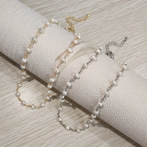 Detailed view of delicate gold and silver chains with natural freshwater pearls and lobster clasp