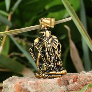Macro shot of a golden Ganesha elephant pendant placed on a natural grey rock