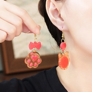 Cat paw and kitten resin earrings with red bows worn by model for jewelry display