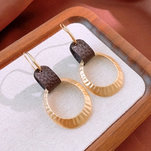 Detail of vintage gold metallic rings and dark brown leather texture on French earrings