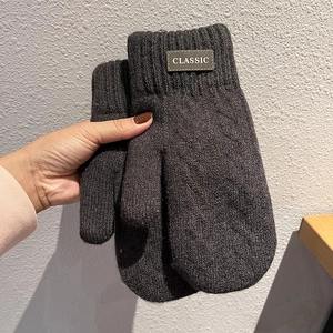 Detailed macro view of dark grey knitted mittens featuring a classic brown leather label