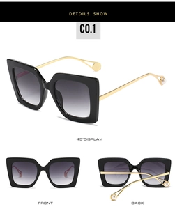 Detail view of square black sunglasses with gold metal temples and pearl tip accents