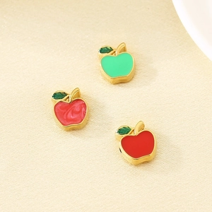 Macro detail of three enamel apple beads in green, red, and pink for DIY jewelry