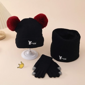 Detail of winter knit set with beanie, scarf, and gloves featuring plush red pompoms