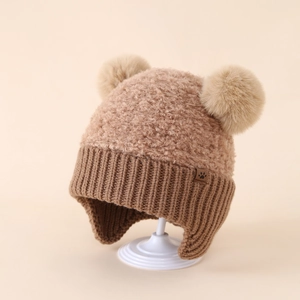 Trama dettagliata di un cappello invernale marrone con pompon in ecopelliccia soffice