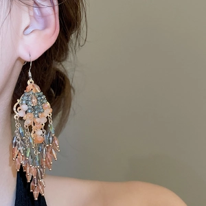 Detail of bohemian long crystal tassel earrings with colorful beads shown on ear