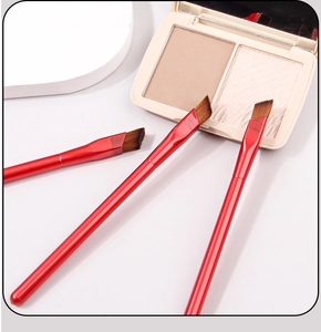 Detailed view of three red angled eyebrow brushes with soft brown bristles and makeup palette