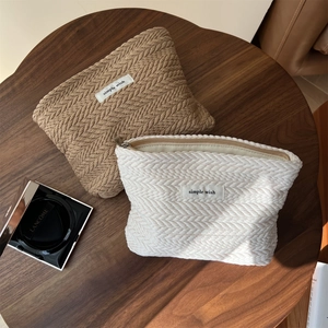 Close-up of herringbone texture on coffee and cream knitted makeup bags with zippers