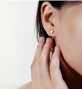 Detail view of a minimalist silver hexagon screw stud earring on a model ear