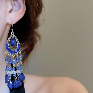 Detail view of bohemian blue crystal beaded tassel earrings worn on ear with drop pendants