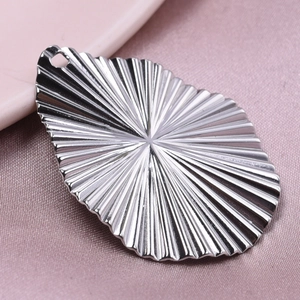 Détail d'un pendentif goutte argenté avec texture radiale sur satin rose