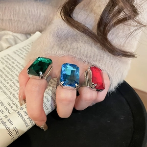 Close-up of three large rectangular crystal rings in green blue and red on silver bands