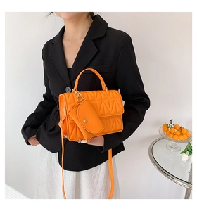 Detail of vibrant orange quilted crossbody bag with matching round coin purse charm