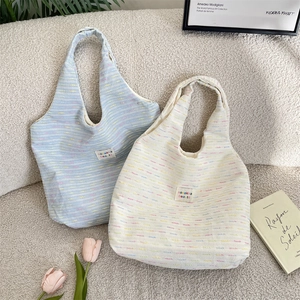 Close-up of textured woven tote bags in light blue and cream with brand logo detail