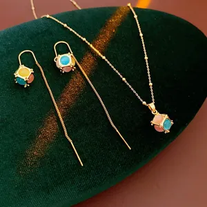 Gold plated opal cube necklace and earrings set on green velvet luxury display
