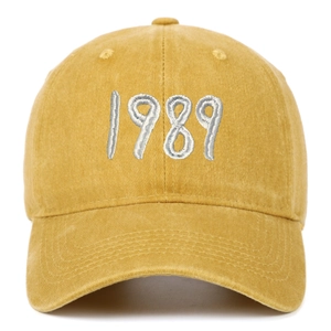 Detailed close-up of white 1989 embroidery on a vintage yellow washed cotton baseball cap