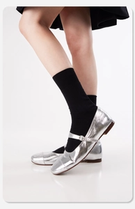 Detailaufnahme von silbernen Mary Jane flachen Schuhen mit schwarzen Socken am Model