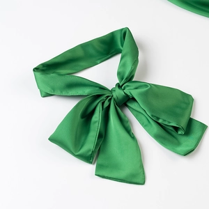 Detailed view of the glossy green satin bow and textured fabric on this blouse