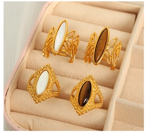 Detail of vintage gold rings with tiger eye and mother of pearl on pink velvet