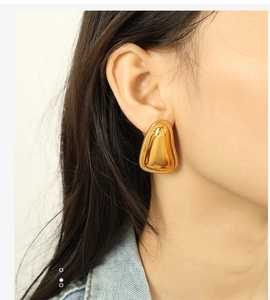 Detailed view of 18K gold geometric paw earrings with textured beaded edges on model