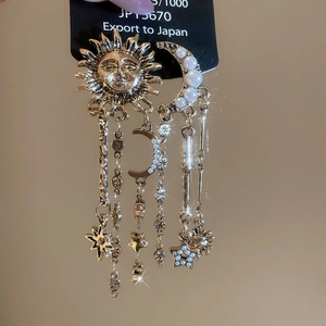 Detail showing vintage gold sun and pearl moon tassel earrings with star charms