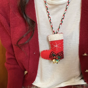 Detail of Christmas stocking plush pendant necklace with bells on red cardigan