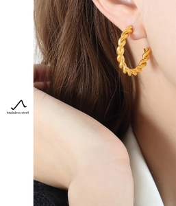 Detail view of bold 18K gold plated stainless steel twisted rope hoop earring on model