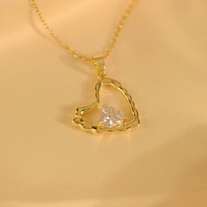 Lava style gold heart pendant necklace with sparkling crystal on beige fabric