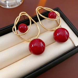 Close-up of geometric gold hoop earrings with red pearls in a black gift jewelry box